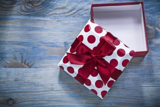 Red gift box with tied bow on wooden board holidays concept
