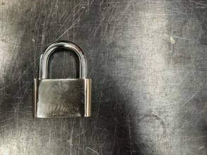 Metallic padlock on metal texture background