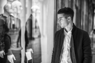 Handsome Young Man in Black Elegant Suit Looking at Displayed Fashion Items in Glass Window