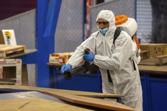 Sofia, Bulgaria - 7 April, 2020: Worker sprays disinfectant outside of ? food market against the
