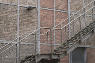 Metal fire escape climbing a brick wall with a lamp