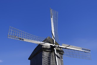 Windmill with wooden sails under a clear blue sky, traditional rural structure, borken,