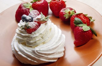 Meringue cake decorated with berries on top on brown plate
