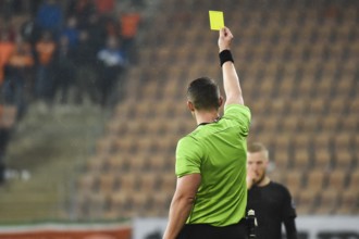 Referee shows footballer yellow card during soccer match at the stadium