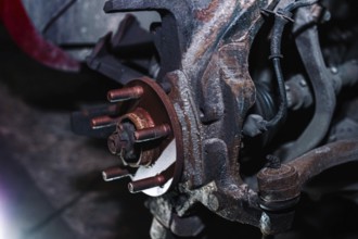 Rusty vehicle brake disc mount without the disc attached in a dim workshop setting