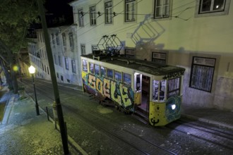 Vintage Lisbon lift (elevator) painted with graffiti on city street at night, Portugal, Europe