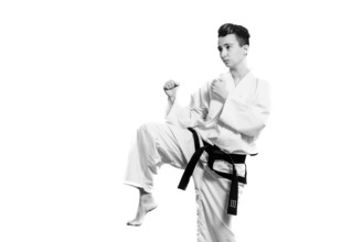 Girl in karate suit kimono in studio at grey background. Female child shows judo or karate stans in