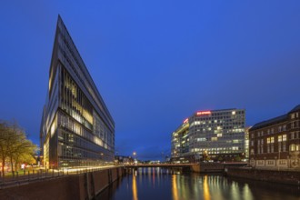 Modern office buildings reflect in the water at night, illuminated by numerous lights, Blue Hour,