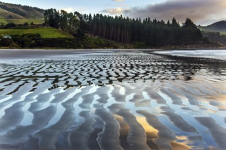 Sunrise over the ocean. Low tide. Strips of sand and water left by the ocean tide. New Zealand,