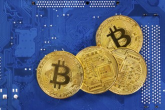 Virtual cryptocurrency money Bitcoin golden coins on a computer printed circuit board PCB. The