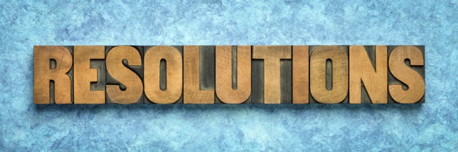 Resolutions word abstract in vintage letterpress wood type blocks against blue textured bark paper,