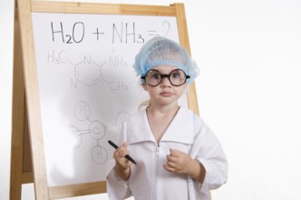 Three year old girl chemist standing at blackboard robe