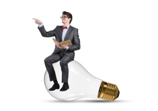 Young businessman sits on an electric light bulb. holds a book in his hands
