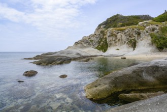 Calm turquoise waters gently lapping against a rocky coastline under a serene sky on elba island,
