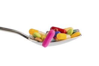 Many colourful tablets on a spoon. Symbolic photo for tablet addiction and misuse of medication.