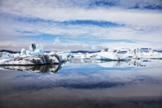 Icebergs and ice floes are reflected in the mirrored water of the ocean Bay. Summer vacation in