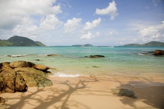Tropical beach with small stones and waves on the foreground