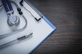 Clip board pen and stethoscope tablet on vintage wooden background medicine concept