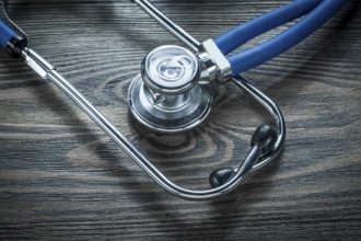 Medical stethoscope on wooden board top view