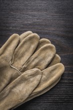 Leather working gloves on vintage wooden board vertical version construction concept