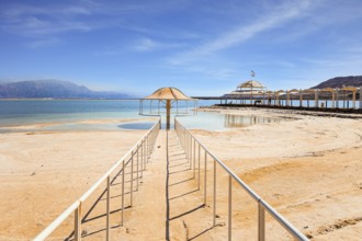 Railings enclose the path to the water. Lovely round umbrella protects from the sun. The drainless