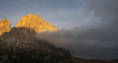 Foggy rocky mountain landscape at sunrise with blue sky. of the Dolomites at Passo Sella South