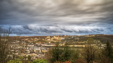 A wide cityscape under a dramatic cloudy sky in an autumnal mood, view of the Bergische Universität