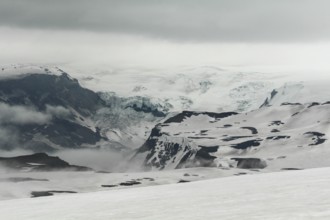 Snowy and foggy white landscape at Fimmvorduhals hiking trail, a glacier in the background,
