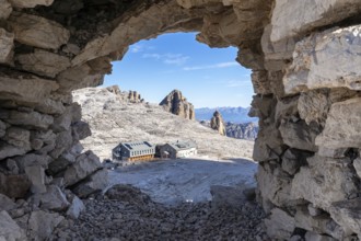 View of the rifugio Boe mountain hut through a stone window in the cairn. Dolomites, Italian Alps.