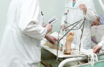 Group of surgeons examine patient with broken leg