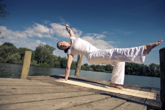 Young woman making yoga exercise at a lake