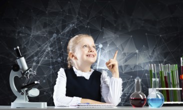 Little girl scientist sitting at desk in elementary science class. Research and education in school