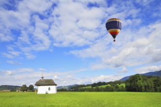 A balloon flies over the charming white village chapel. Southern France