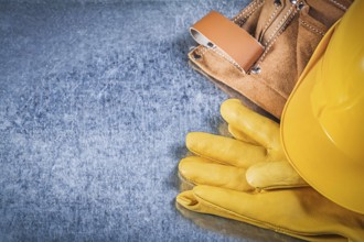 Safety gloves tool belt hard hat on metallic background construction concept