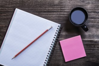 Open notepad pencil reminder note and cup of coffee on wooden board office concept