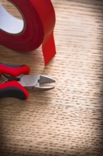 Vertical view nippers with insulating tape on wooden board
