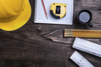 Copybook pencil blueprints instruments of measurement hard hat and coffee on pine wood board