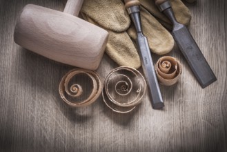 Wooden mallet curled up shavings firmer chisels leather gloves on wood board construction concept