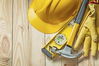 Claw hammer construction level leather gloves and construction helmet on wood