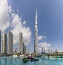 A picture of the Burj Khalifa towering the nearby Downtown Dubai buildings and the blue waters of