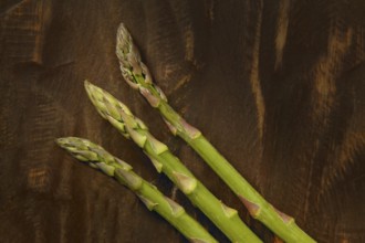 Three asparagus over dark brown wooden background