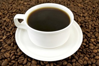 Coffee in a white porcelain cup on the background of the coffee beans
