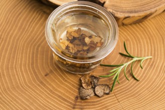 Sliced black truffle in olive oil in small jar and fresh rosemary