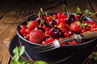 Bowl with different fruits such as strawberry, red currant, and cherry