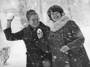 Winter in the 1960s. Two young women is aiming and about to throw snowballs at the photographer.