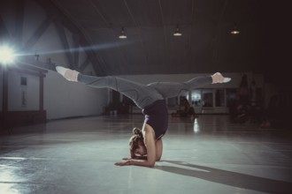 Young attractive yogi woman practicing yoga concept, standing in variation of Pincha Mayurasana