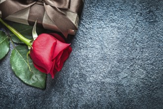 Gift box with brown ribbon red rose on black background holidays concept