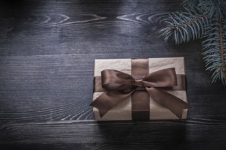 Pine branch wrapped gift box on wooden board holiday concept