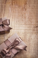 Conceptual copyspace photo two brown paper giftboxes with ribbons on vintage wooden board