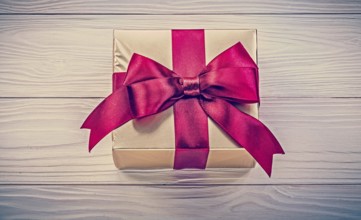 Wrapped present box on wooden board directly above holidays concept